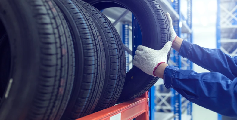 A person handling a tyre in a manufacturing plant.