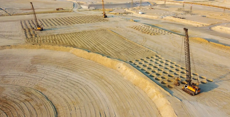 A large-scale construction site featuring dynamic compaction operations.